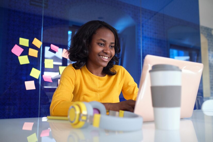 african-american-young-woman-smiling-working-with-her-laptop-office_371418-847